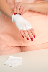 Cosmetologist in workwear wearing white bamboo fingerless gloves on her hands