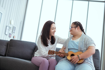 Autistic girl plays the guitar with her mom at her holiday home.