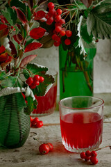 on a wooden table, next to red berries, a cut apple and glass vases with autumn bouquets. Autumn cozy home greeting card