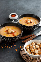 Lentil cream soup with paprika and crouton in black ceramic bowls