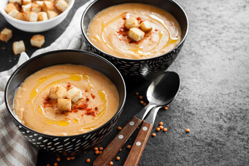 Lentil cream soup with paprika and crouton in black ceramic bowls
