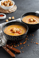 Lentil cream soup with paprika and crouton in black ceramic bowls