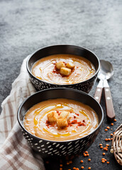 Lentil cream soup with paprika and crouton in black ceramic bowls