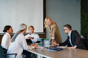 Multiracial men and women discussing project during meeting in office