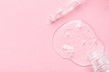 Bottle neck and glass pipette tip with spilled clear gel on light pink surface close upper view....