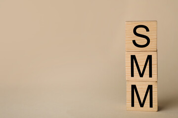Wooden cubes with abbreviation SMM (Social media marketing) on beige background. Space for text