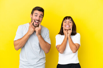 Young couple isolated on yellow background smiling with a happy and pleasant expression