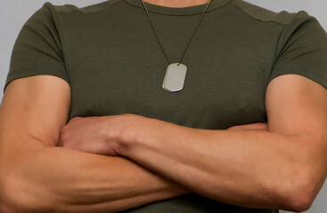 A soldier in a T-shirt with a military name medallion around his neck. Strong physique of a...