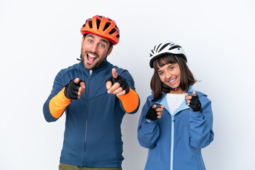 Young cyclist couple isolated on white background points finger at you while smiling