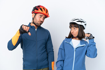 Young cyclist couple isolated on white background showing thumb down sign with negative expression