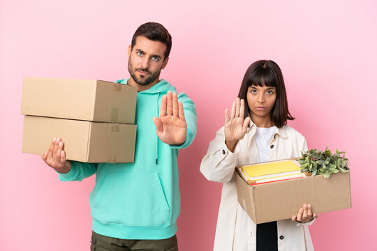 Young Beauty Couple Moving In New Home Among Boxes Isolated On Pink Background Making Stop Gesture Denying A Situation That Thinks Wrong