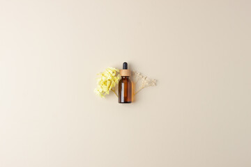 Cosmetic bottle with flowers on pastel beige background. Flat lay, copy space