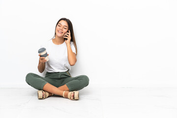 Fototapeta na wymiar Teenager girl sitting on the floor holding coffee to take away and a mobile