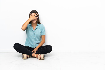 Fototapeta na wymiar Teenager girl sitting on the floor covering eyes by hands and smiling