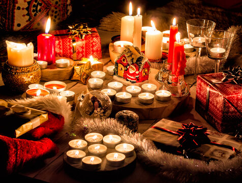 Christmas still life with candles of different size and shape, decorative round wood, souvenir Santa Claus clay house, gift boxes, christmas tree toy.