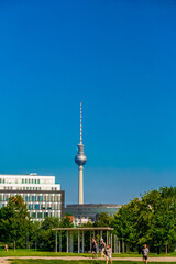 Naklejka premium Beautiful view of the Berlin Television Tower (Berliner Fernsehturm) with its impressive sphere and spire in the background of the capital city in Germany on a nice sunny summer day with a blue sky.