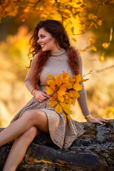 a beautiful woman posing on a log of an old tree in autumn, the colors of autumn