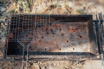 Top view of an empty grill and an old, dirty grill grate. Barbecue season, summer vacation. Cooking on the fire. Cooking in the fresh air. Items for cooking food on an open fire.