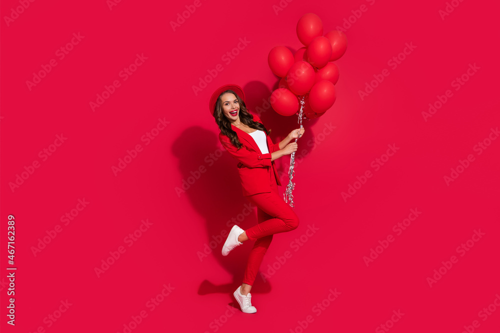 Sticker photo of charming excited young woman wear suit jacket cap smiling holding balloons isolated red col