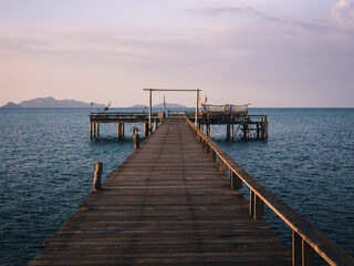 Obraz premium Scenic view of peaceful long straight wooden pier over blue water in evening before sunset. Koh Mak Island, Trat, Thailand. Minimal background.