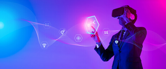 Young man using glasses of virtual reality on dark background. Smartphone using with VR headset,virtual reality,future technology concept.Asian man using VR glasses in colorful neon lights.

