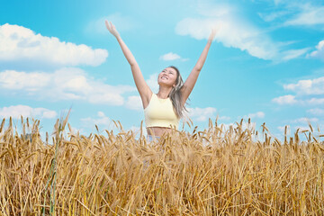 young asian girl smiling walks through a wheat field throwing up her hands