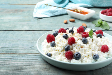 Delicious cottage cheese with fresh berries and honey served on light blue wooden table, space for text. Tasty breakfast