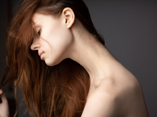 woman with bare shoulders basing red hair clear skin