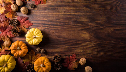 Autumn composition. Pumpkin, pine cone and autumn leaves on dark wooden background. Flat lay, top view with copy space