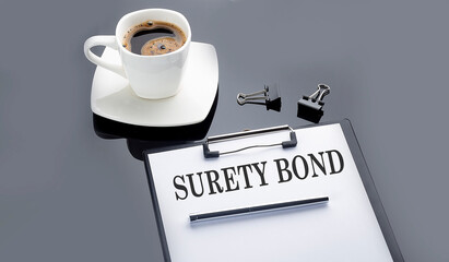 SURETY BOND text on paper sheet with coffee on the black background