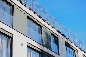 gray cement brick wall of corporate building facade with panoramic windows on blue sky background
