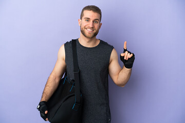 Young sport man with sport bag isolated on white background pointing up a great idea
