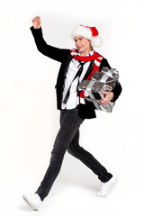 Handsome smiling man in a New Year's hat and scarf hurries with gifts. Studio, white background. New Year advertising