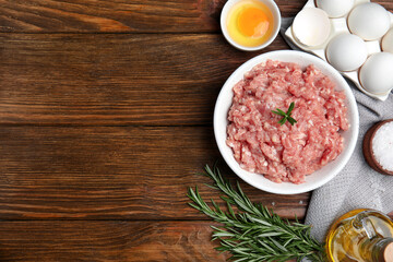 Raw chicken minced meat and ingredients on wooden table, flat lay. Space for text