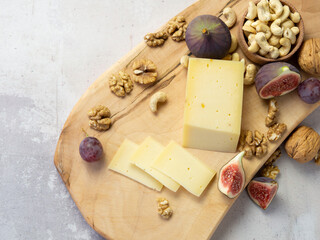 Slicing cheese with fruits - nuts and figs on a wooden board. Delicious snack