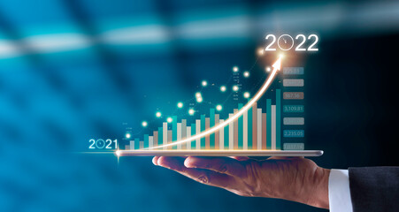 Businessman hand holding tablet showing graph economic growth target success from 2021 to 2022....