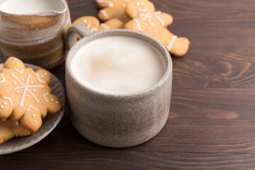 Coffee with milk and gingerbread cookies on wooden background. Winter hot drinks.