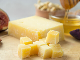 Pieces of aged cheese, nuts, figs and honey on a cutting board,