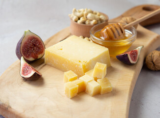 Pieces of aged cheese, nuts, figs and honey on a cutting board,
