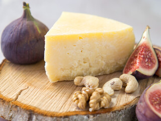 variety of hard cheese with figs and nuts on a wooden cutting board