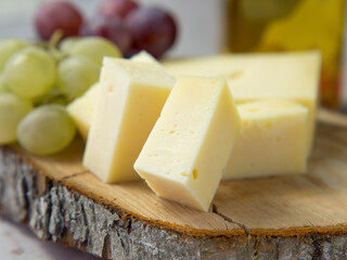 Light meal with sliced cheese next to a bunch of white and red grapes