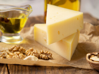 pieces of cheese on parchment paper with nuts and olive oil on an old wooden table