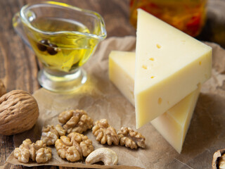 pieces of cheese on parchment paper with nuts and olive oil on an old wooden table