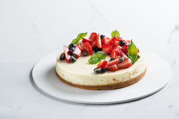 Cheesecake with fresh strawberries and blueberries on a light background. Classic cheesecake