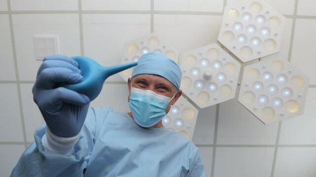 Doctor with an enema in his hands stands above the patient. Spiteful physician in anticipation of medical procedure.