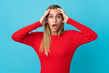 Young blonde woman isolated on blue background with surprise expression