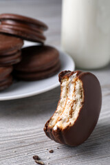 Tasty bitten choco pie on white wooden table, closeup view