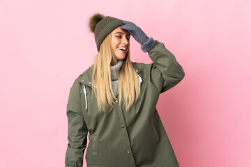 Fototapeta premium Young woman with winter hat isolated on pink background smiling a lot