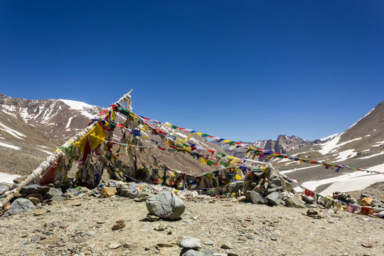 Colorful tibetan Buddhist prayer flags on top of the high altitude pass of Shingo La over the Great Himalayan range in Zanskar.
