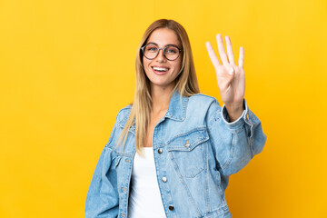 Young blonde woman isolated on yellow background happy and counting four with fingers